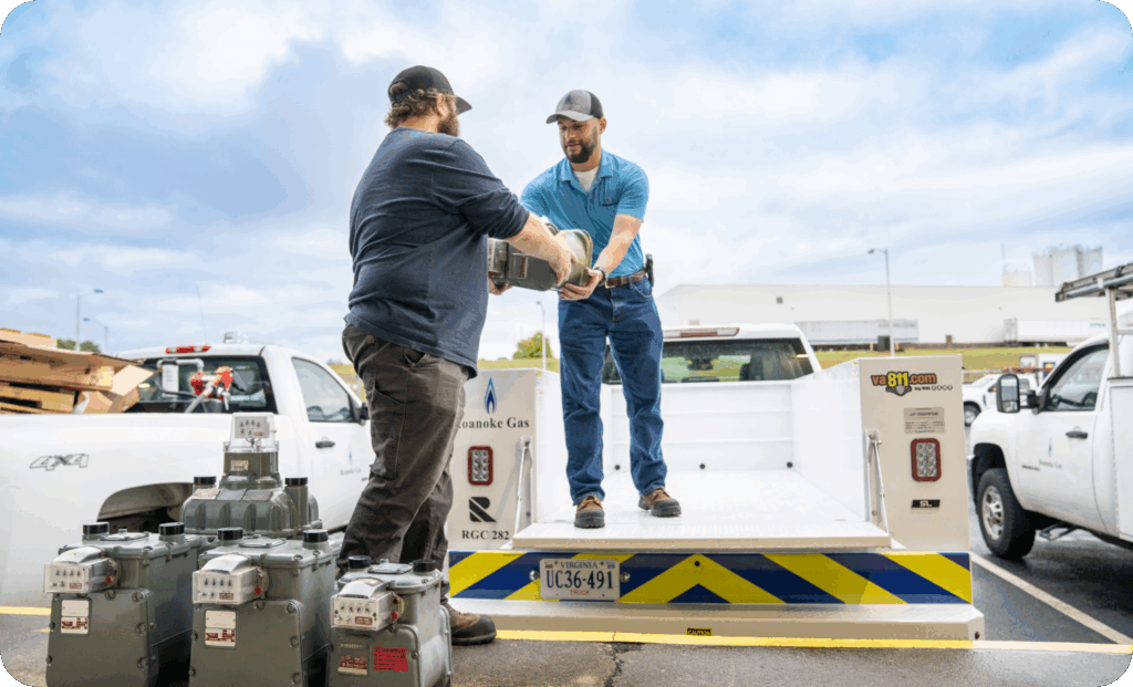 Two men loading items into the back of a work truck.