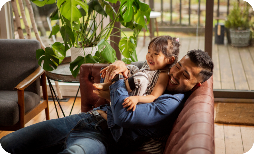 A man relaxing on a couch holding a young child