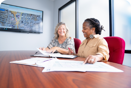 Two women seated at a conference table reviewing papers.