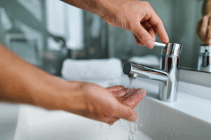 A person holding their hand under a running sink faucet.