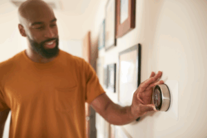 A person adjusting a thermostat.