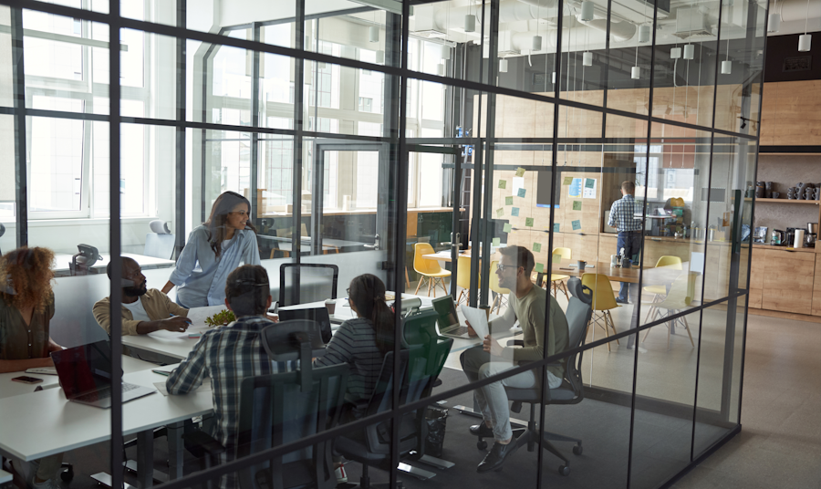 People seated around a conference table in a room with all of the walls made of glass