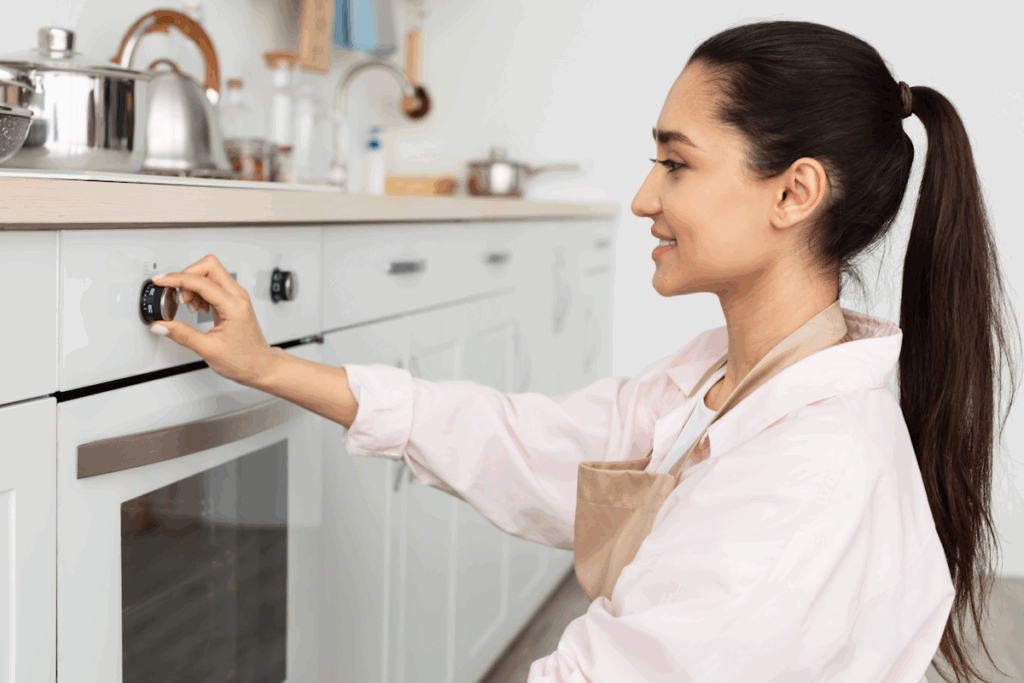 A woman in a kitchen turning a knob on an oven
