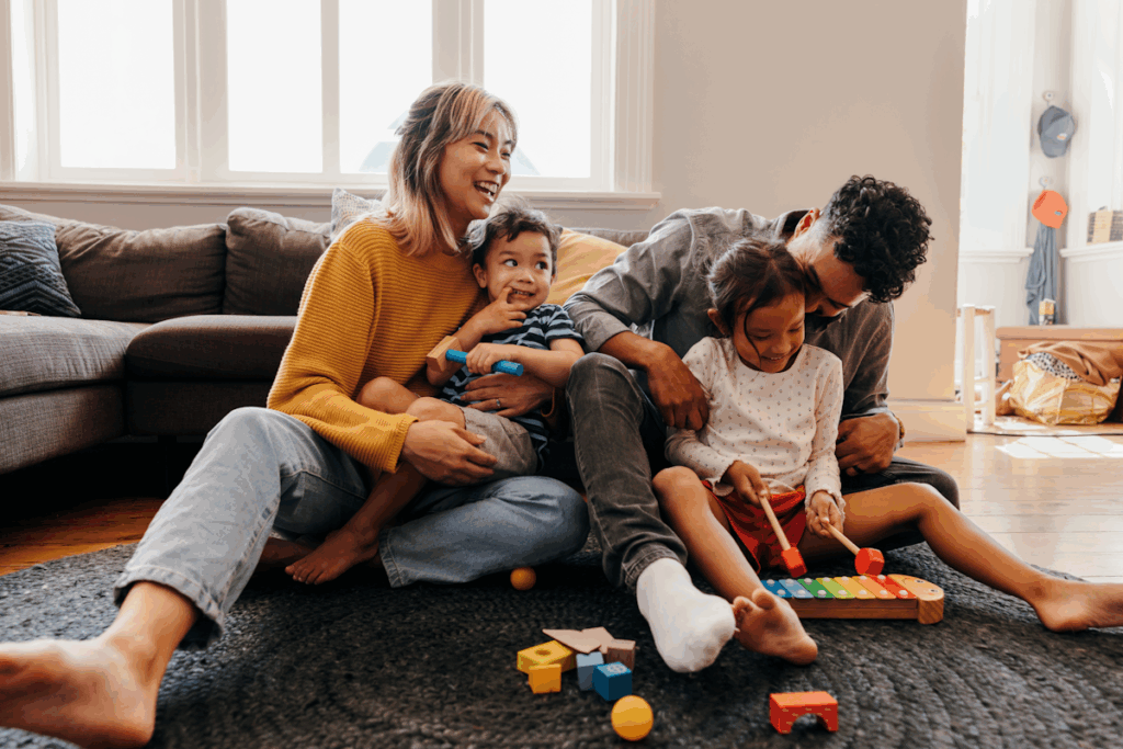A couple playing with two young children on the living room floor.