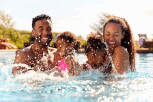 A couple and two young children splashing in a pool.