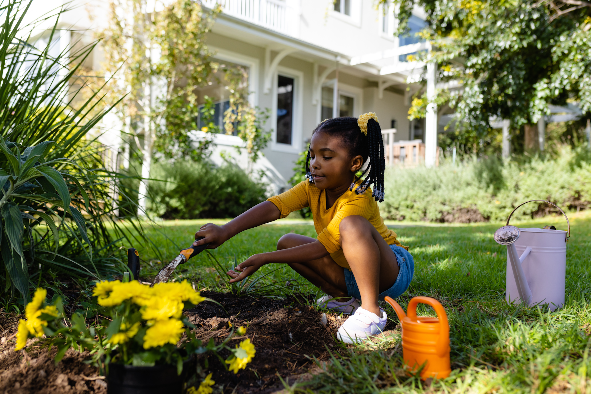 A young girl digging in her yard to plant some flowers