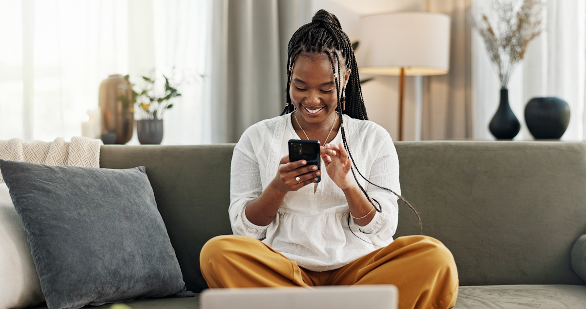 A woman seated on a couch looking at her phone.