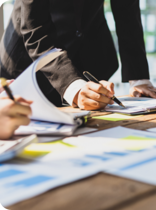 A closeup of people at a table writing on stacks of paper.