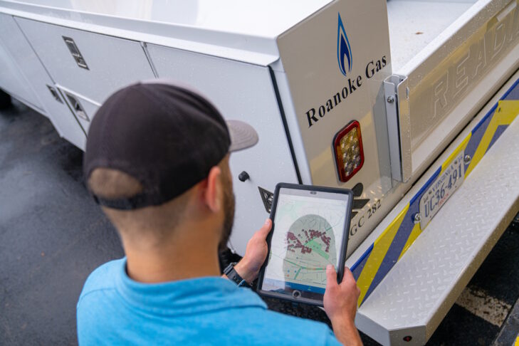 A worker standing at the back of a truck and looking at a tablet